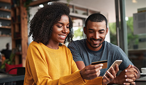 Two people smiling at a phone about to make a purchase