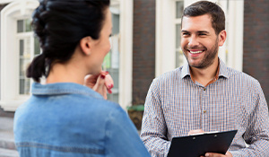 Man smiling with clipboard talking to a woman 