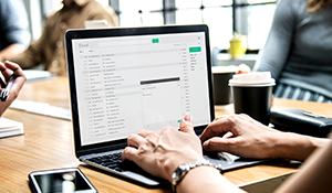 Person at a conference table checking their email on a laptop