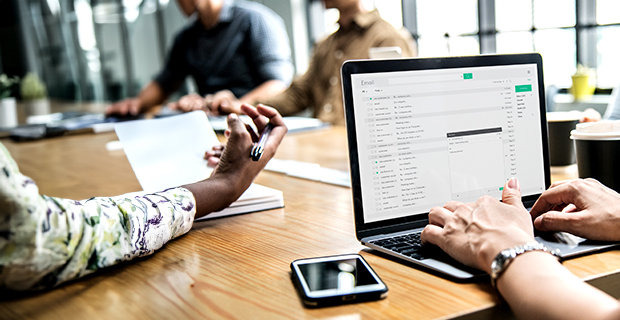 Person at a conference table checking their email on a laptop